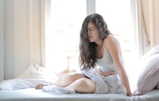Prather-Bedwetting 1 Person sitting up in bed holding their stomach.