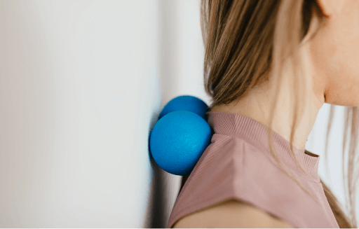 Prather-Shoulder Pain 1 Person rolling lacrosse balls between their shoulders and a wall.