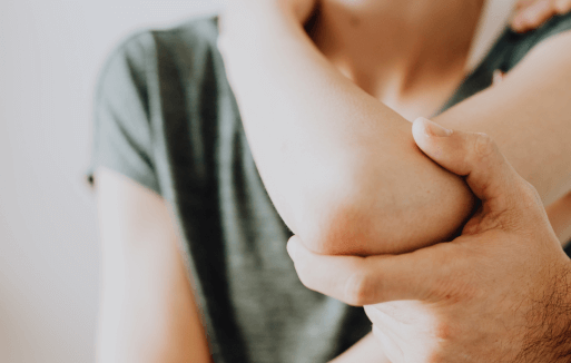Prather-Elbow Pain 1 Person holding their arm in front of them and a chiropractor's hand adjusting their elbow.