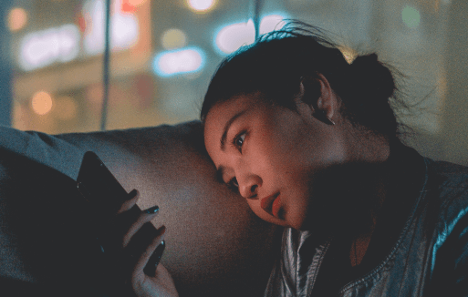 Prather-Sleeping Problems 2 Person sitting on a couch at night looking at their phone.